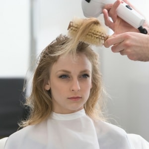 Femme se faisant faire un brushing avec un sèche cheveux 